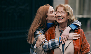 Dekle, ki je srečalo babico na sprehodu v mestu, jo objema in poljublja na lice.