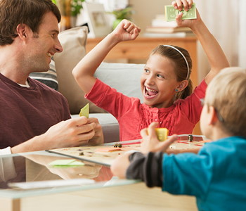 Oče z otrokoma uživa v družabni igri Monopoli.