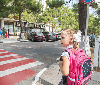 Deklica na prehodu za pešce čaka na varen trenutek za prečkanje