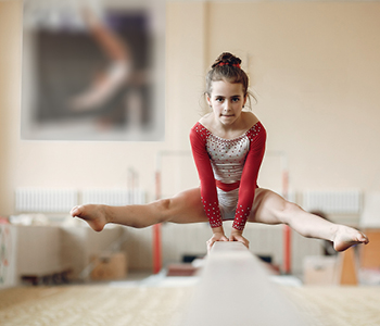 Mlada gimnastičarka izvaja vajo na bradlji, po tem, ko je okrevala po poškodbi kolena.