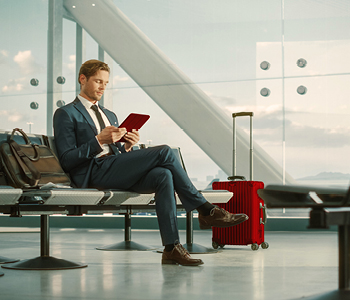 Poslovnež sedi v čakalnici na letališču in čaka svoje letalo.