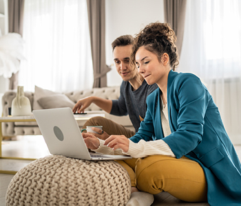 Moški in ženska sedita za računalnikom - lotila sta se urejanja osebnega proračuna s pravilom 50-30-20.