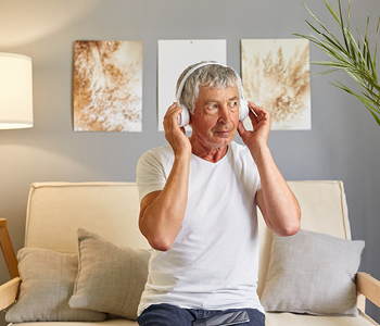 Starejši gospod uživa v poslušanju glasbe na slušalkah.