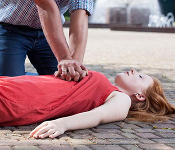 Moški na cesti nudi prvo pomoč dekletu z zastojem srca.
