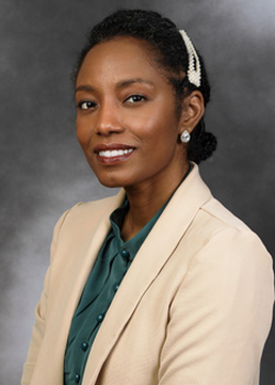 Headshot of Sarah Mcqueen, who smiles while wearing a green blouse and tan blazer