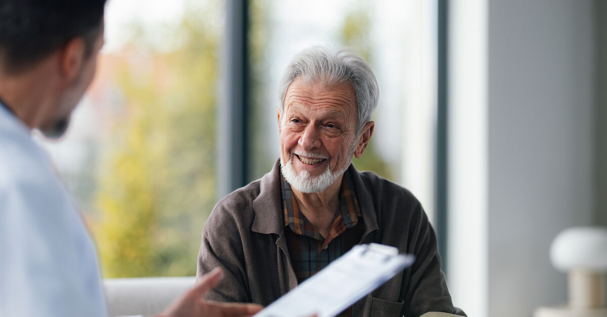 A senior male patient speaks with a doctor about cancer symptoms