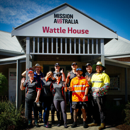 A group of males and females stand outside Wattle House, a Mission Australia service.