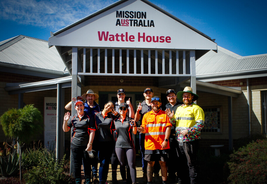 A group of males and females stand outside Wattle House, a Mission Australia service.