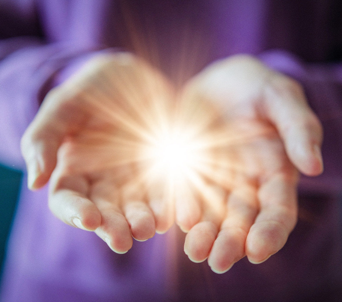 Two hands held together, with a warm glowing light between them. Purple background, branding echos international women's day branding