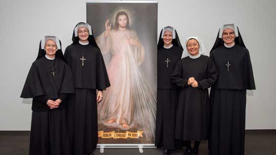 The Sisters of Our Lady of Mercy standing with an image of the Merciful Jesus