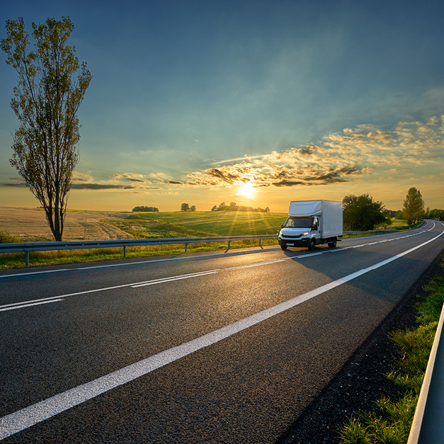 A moving truck driving on a highway at sunset