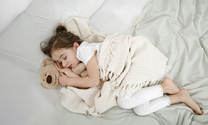 Spokojen trenutek za malčka, ki je zaspal v postelji, medtem ko je smrčanje pri otroku razlog za skrb staršev.