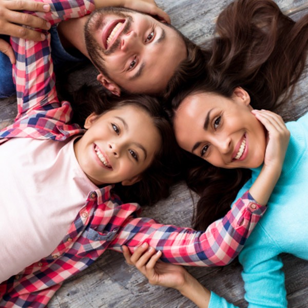 smiling family laying off on the floor with their heading together