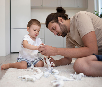 Mlad oče se z malčkom igra v dnevni sobi in mu pomaga razvijati prostorsko predstavo, pa tudi zdravo navezanost