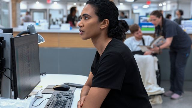 Dr. Samira Mohan sits at a computer station in a hospital, focused on the screen.