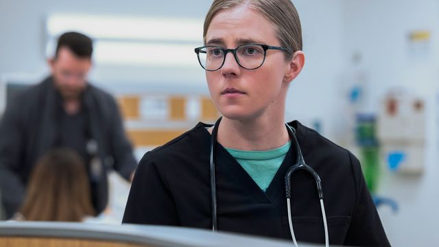 Dr. Melissa “Mel” King stands at a hospital station, wearing scrubs and a stethoscope