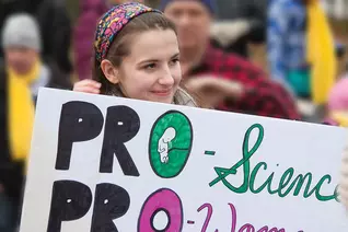 Girl stands outside at the March for life holding a sign