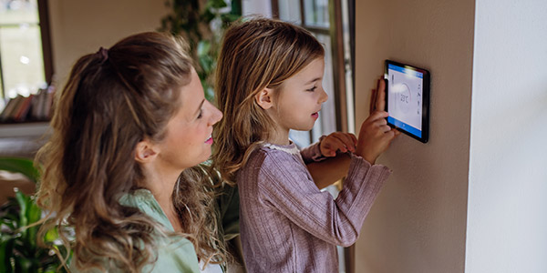 mother and daughter adjusting thermostat