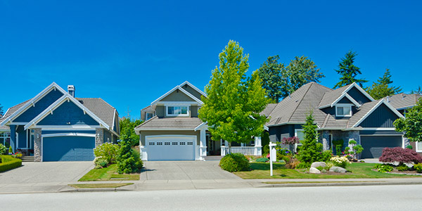 A row of vinyl and stone homes with well maintained lawns