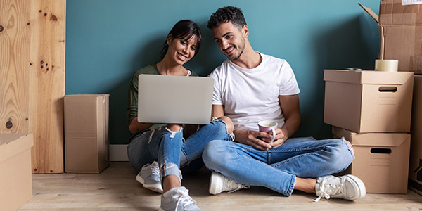 couple sitting with a laptop on the floor of their new home