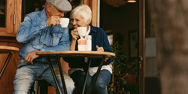 happy senior couple sitting outside a cafe and drinking coffee