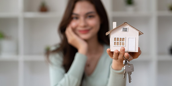 woman holding a house model and house keys