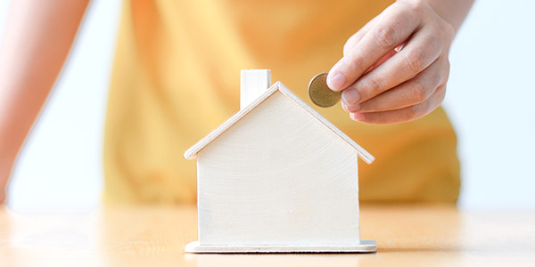 putting a coin in a house piggy bank