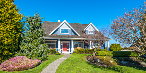 A blue two-story, vinyl-sided house sits on a well manicured lawn