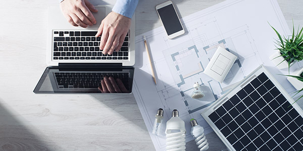 A laptop sits on a table top with schematics and various light bulbs