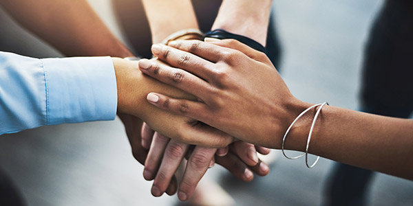 Black hands stacked on top of each other
