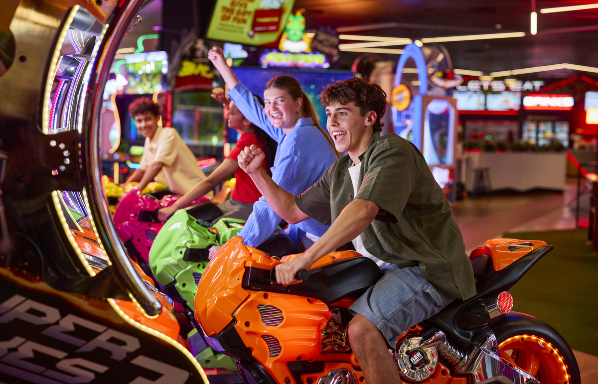 Friends playing arcade motorbike game at Timezone