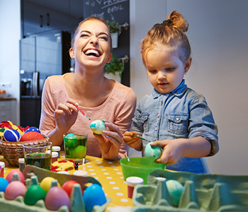 Malčica z mamo in teto izdeluje okraske za veliko noč in se pri tem zabava.
