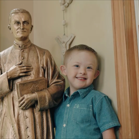 Mikey Schachle with statue of Father McGivney.