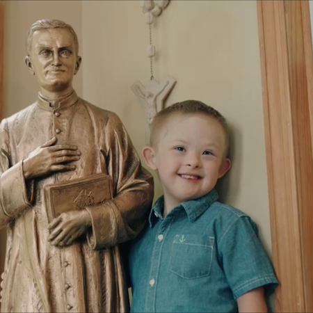 Mikey Schachle with statue of Father McGivney.