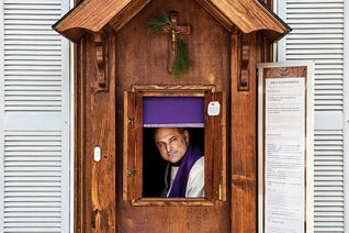 Father Seamus Griesbach sits at the confessional he built to fit in the window of the rectory of Our Lady of the Rosary Parish in Sabattus, Maine