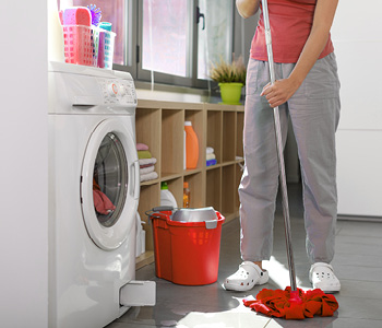 Ženska čisti tla, ker ji pralni stroj pušča vodo