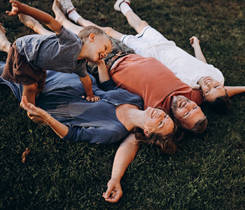 Družina leži v travi in uživa občutek varnosti, ki jim ga daje življenjsko zavarovanje obeh staršev.