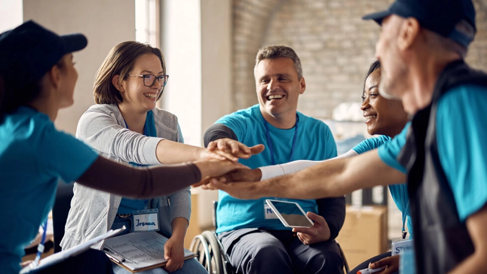 Photo of five volunteers smiling and joining hands in a circle