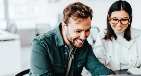 Smiling male and female professionals looking at laptop 