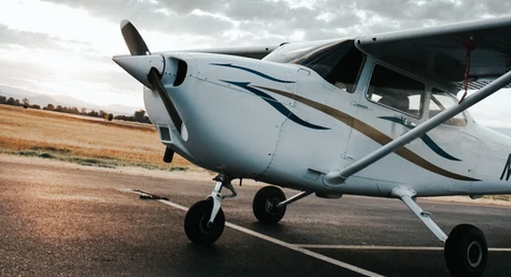A small general aviation airplane parked on the ramp with the sunset in the background. 